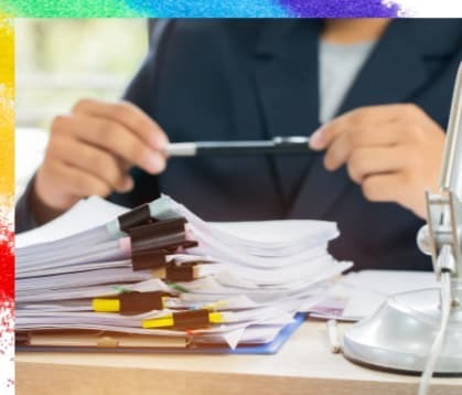 複数の束になった書類を前にペンを握る女性の画像